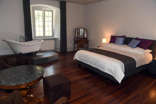 a bedroom with a large bed and a bath tub at Auberge de Bellelay Restaurant Chez Aron Balde in Bellelay