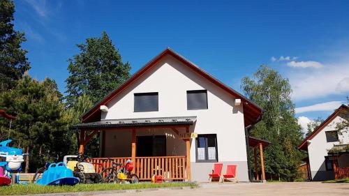 una casa blanca con un parque infantil delante de ella en Domki RADAWA na Kliszówce, en Radawa