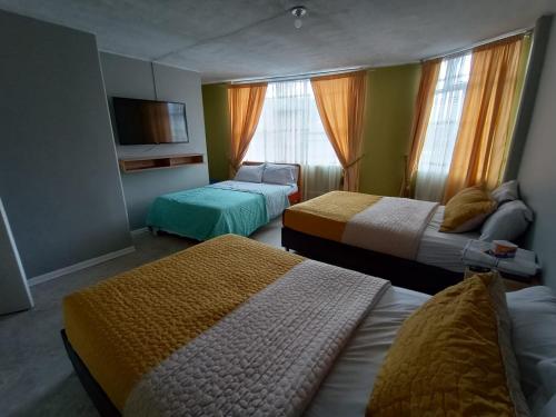 Cette chambre comprend deux lits et une télévision. dans l'établissement HOTEL DINO, à Pasto