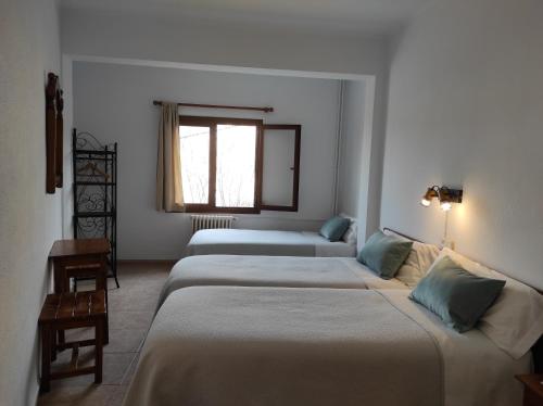 a room with three beds and a window at Hostal Nadal in Sóller