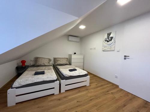 biała sypialnia z 2 łóżkami i schodami w obiekcie Apartmán Světla w mieście Pardubice