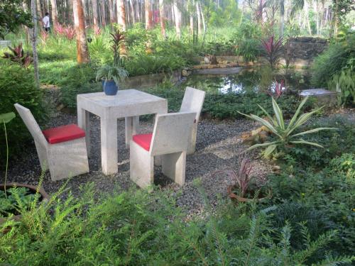 a table and chairs in a garden with a pond at Manora Garden in Phangnga