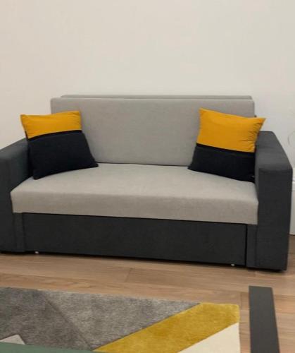 a grey couch with two yellow pillows on it at Zakarias Apartments in Miercurea-Ciuc