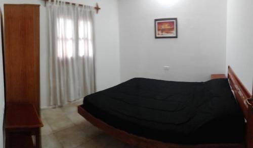 1 dormitorio con cama negra y ventana en El Viejo Carreton en Villa Unión