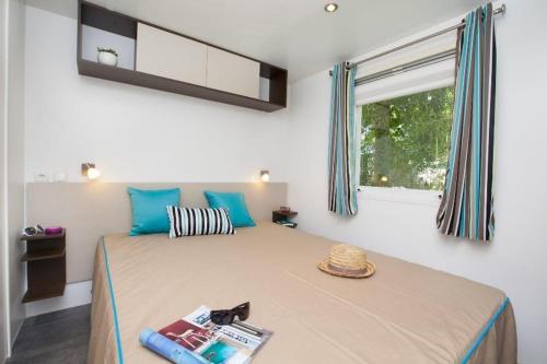une chambre avec un lit avec des oreillers bleus et une fenêtre dans l'établissement Camping Le Pre Saint-Andre, à Souvignargues