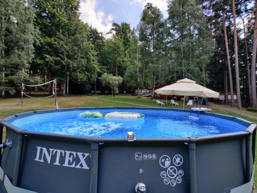 a large hot tub in a yard with an umbrella at Ośrodek leśny Rajsko w Zapuście in Zapusta