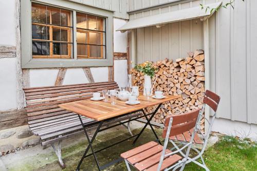 a wooden table and a bench and a pile of fire wood at Fischerhäuser Romanshorn in Romanshorn