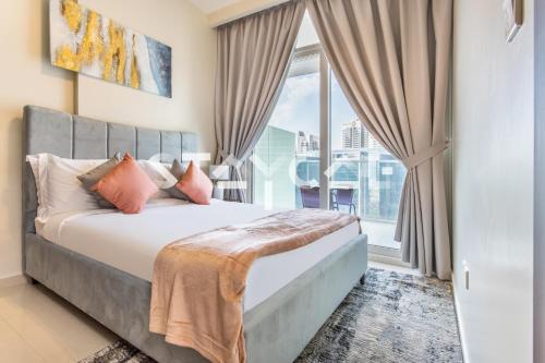 sypialnia z łóżkiem i dużym oknem w obiekcie Staycae Holiday Homes - Reva w Dubaju