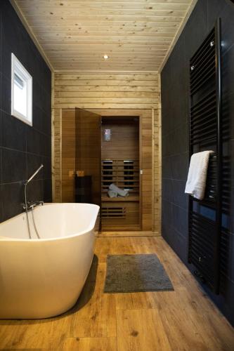 a bathroom with a white tub and wooden walls at Vakantiehuisje Jipué met bubbelbad en sauna in Bruchterveld