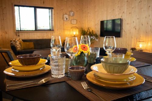 a wooden table with plates and wine glasses on it at Vakantiehuisje Jipué met sauna en bubbelbad. in Bruchterveld