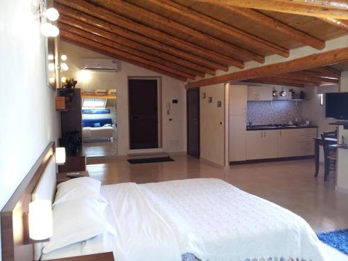 a bedroom with a white bed and a kitchen at B&B Suite in Viagrande