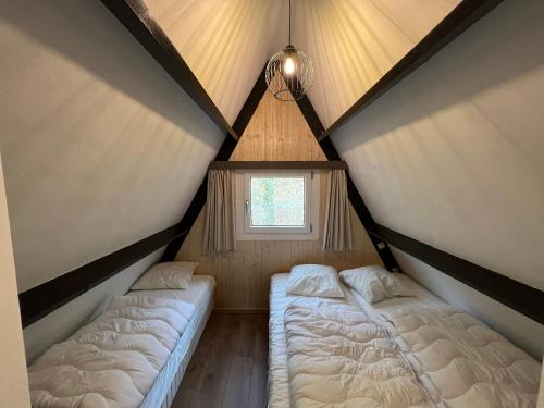 2 camas en una habitación pequeña con ventana en Bos Chalet Durbuy, en Durbuy