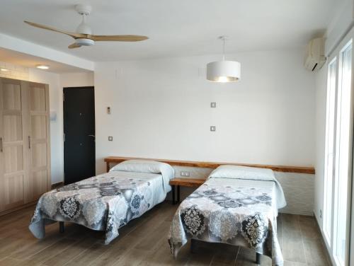 Cette chambre comprend deux lits et un ventilateur de plafond. dans l'établissement Casa Samsara Yaranda, à Dénia