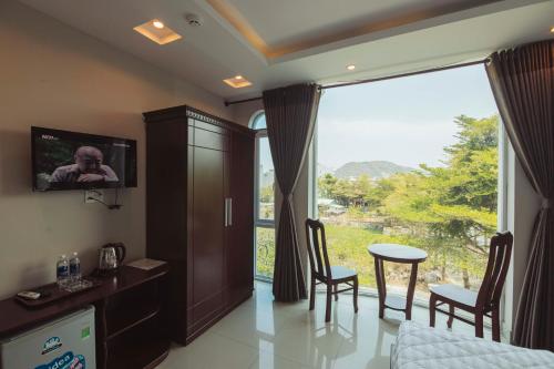 um quarto com uma grande janela e uma mesa e cadeiras em Biển Vàng - New Golden Sea em Vung Tau