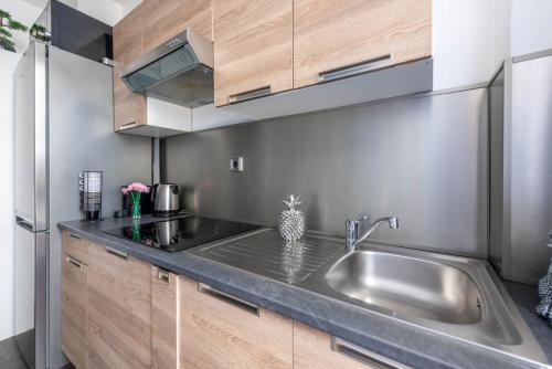 eine Küche mit einer Spüle aus Edelstahl und Holzschränken in der Unterkunft Nice Central Art Deco Flat 45 m² in Nizza