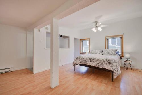a white bedroom with a bed and a ceiling fan at 2-storey house with garage and interior terrace in Quebec City