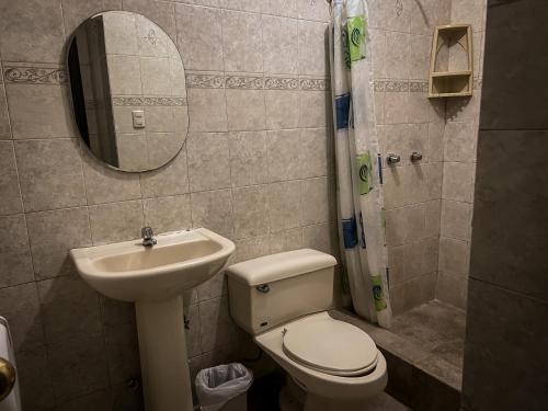 a bathroom with a toilet and a sink and a mirror at Hostal Wilson Inn in Guayaquil