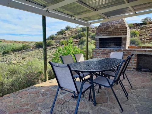 a table and chairs on a patio with a fireplace at Ganora Guest Farm, Camping and Excursions in Nieu-Bethesda