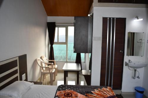 a bedroom with a bed and a sink and a window at Hotel Soham Retreat in Mahabaleshwar