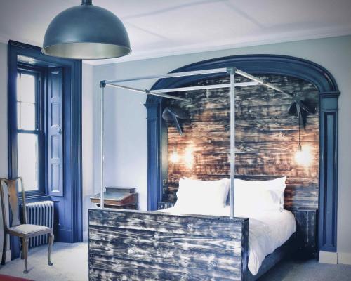 a bedroom with a canopy bed with a brick wall at Suie Hunting Lodge in Killin