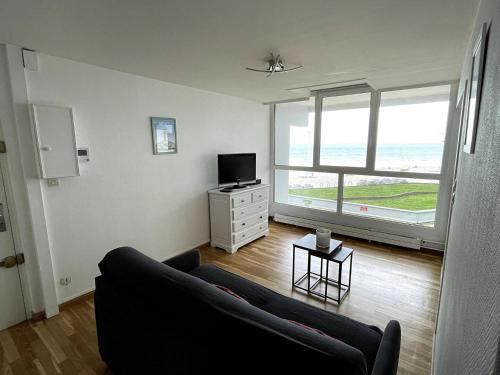 uma sala de estar com um sofá e uma televisão em Type 3 entièrement rénové vue pleine mer Malo em Malo-les-Bains