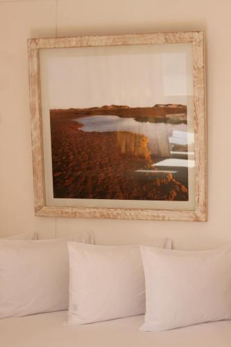 a picture hanging above a bed with white pillows at Lagon energy dakhla in Dakhla