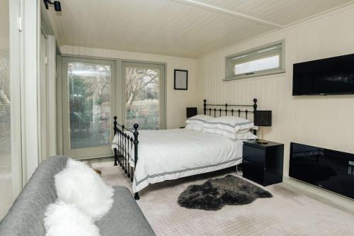 een slaapkamer met een bed en een tv en een bank bij Cuckoo’s Hideaway in Buckinghamshire