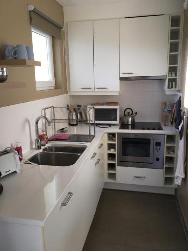 une cuisine avec des armoires blanches et un évier dans l'établissement «  Le Sand-Wedge » appartement vue mer, à Wimereux