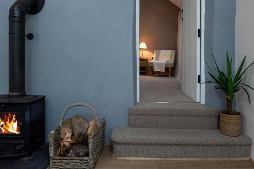a hallway with a fireplace and stairs with a basket at Ceunant Bach in Bethesda
