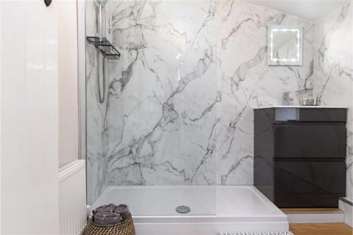 a bathroom with a tub and a marble wall at Ceunant Bach in Bethesda