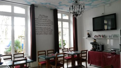 a dining room with tables and chairs and windows at Hôtel De Paris in Charleville-Mézières