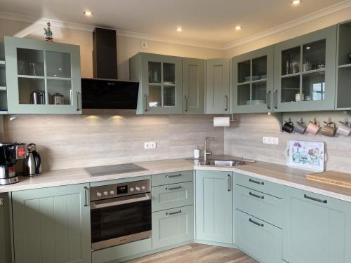 a kitchen with green cabinets and a sink at Ferienwohnung Ostseetraum in Damp