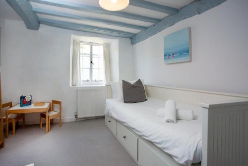1 dormitorio con cama, mesa y ventana en Fox Cottage, en Sidbury