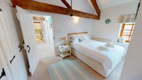 a white bedroom with a bed and a window at Stables Barn in East Budleigh