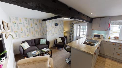 a kitchen and a living room with a couch at Cider Cottage in Sidmouth