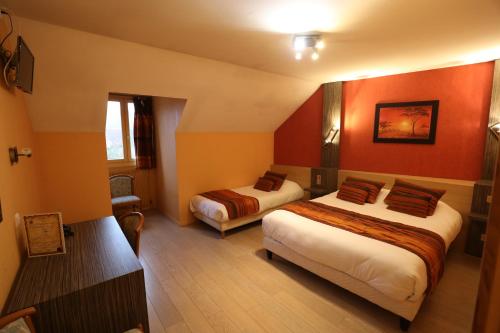 two beds in a room with red walls at Logis Le Bourguignon in Bèze