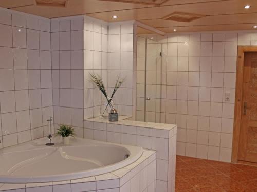 ein weißes Bad mit einer Badewanne und einem Spiegel in der Unterkunft Ferienwohnung Kohlstatt in Kiefersfelden