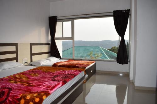 a bedroom with two beds and a large window at Hotel Soham Retreat in Mahabaleshwar