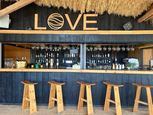 a bar with four wooden stools and a sign that reads love at Lagon energy dakhla in Dakhla