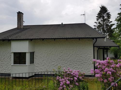 a white house with a black roof and pink flowers at Ekonomirum i Karlstad 