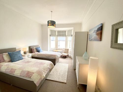 a bedroom with two beds and a living room at Merrifield House in Sidmouth