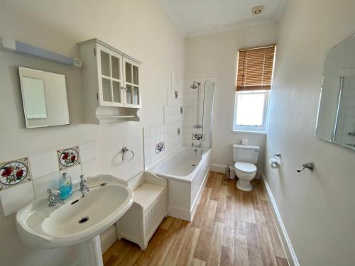 a bathroom with a sink and a tub and a toilet at Merrifield House in Sidmouth
