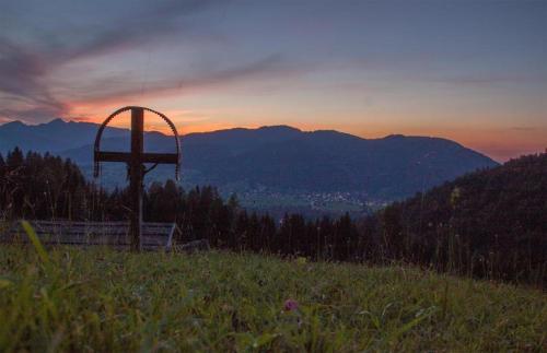 a cross on top of a hill with the sunset at Haus Abendsonne in Reit im Winkl