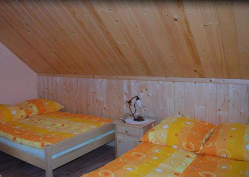 two beds in a room with a wooden ceiling at Jacowa Chata in Istebna