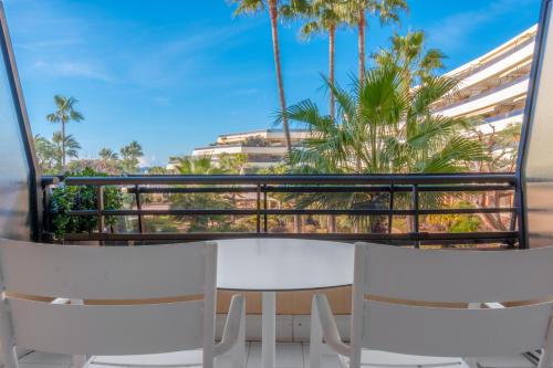 d'un balcon avec deux chaises blanches et des palmiers. dans l'établissement Holiday Inn Nice - Port St Laurent by IHG, à Saint-Laurent-du-Var