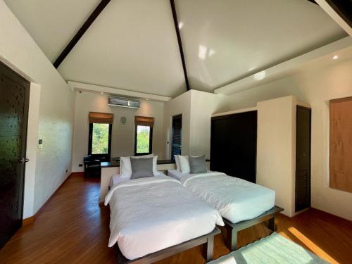 twee bedden in een grote kamer met houten vloeren bij HINSAMAAN POOL VILLA in Koh Samui 
