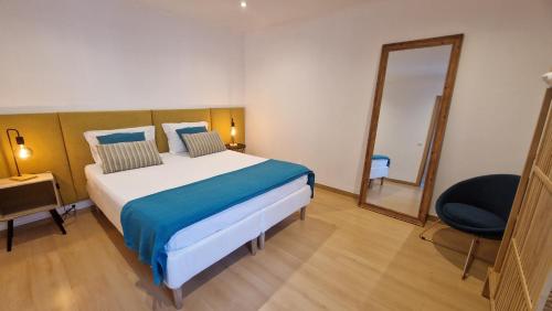 a bedroom with a bed and a mirror and a chair at Santa Cruz Villas in Santa Cruz das Flores