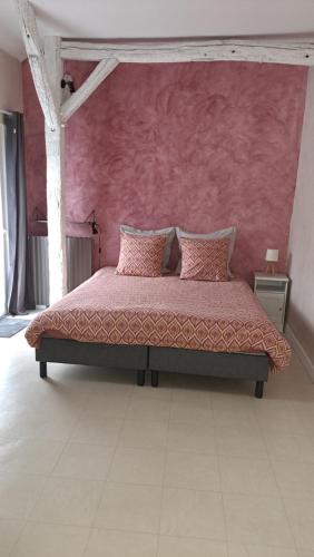 a bedroom with a bed with a pink wall at Moulin Béchereau in Mer