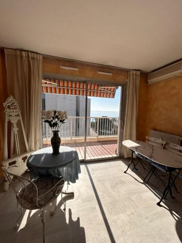 un salon avec une table et une grande fenêtre dans l'établissement Appartamento con vista Promenade, à Nice