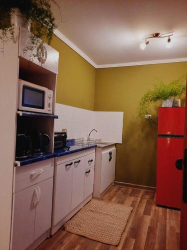 a kitchen with a microwave and a red refrigerator at Cabaña Mi calma in Coquimbo
